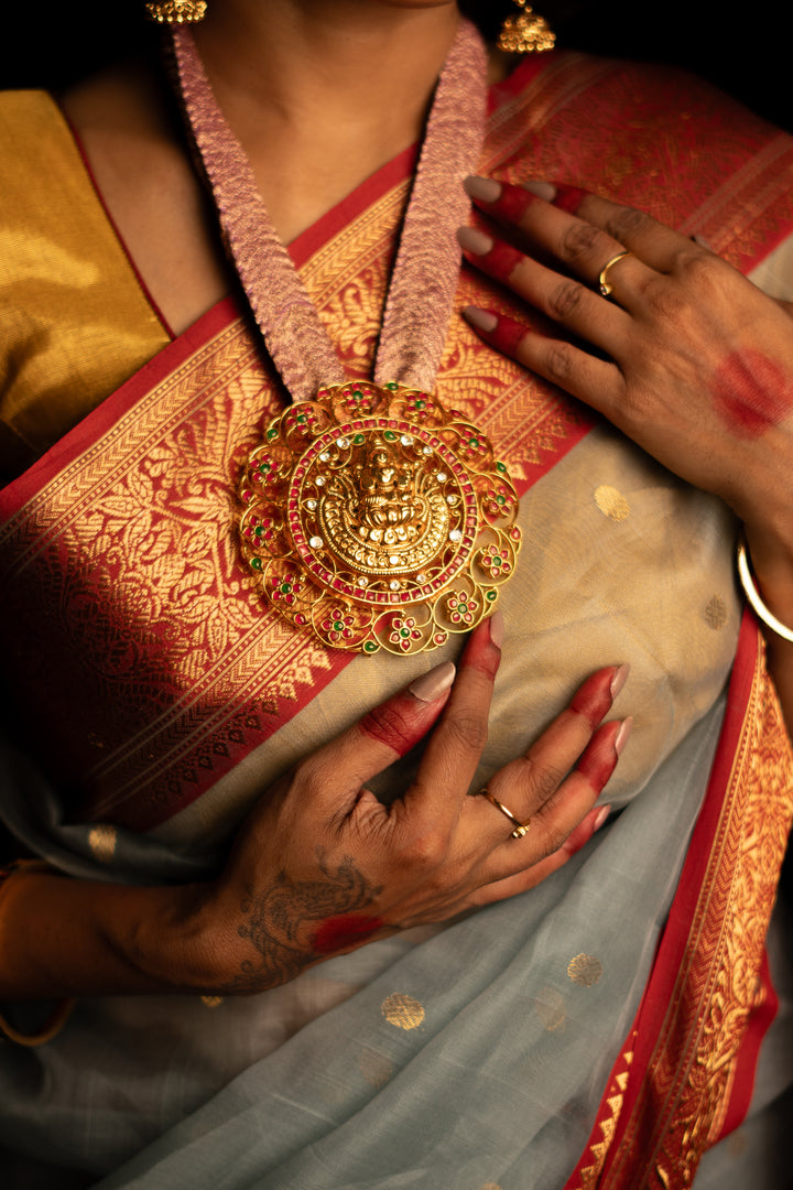 A zoomed image of women, dressed up and is posing by wearing beautiful grey silk saree with matching jewelry.