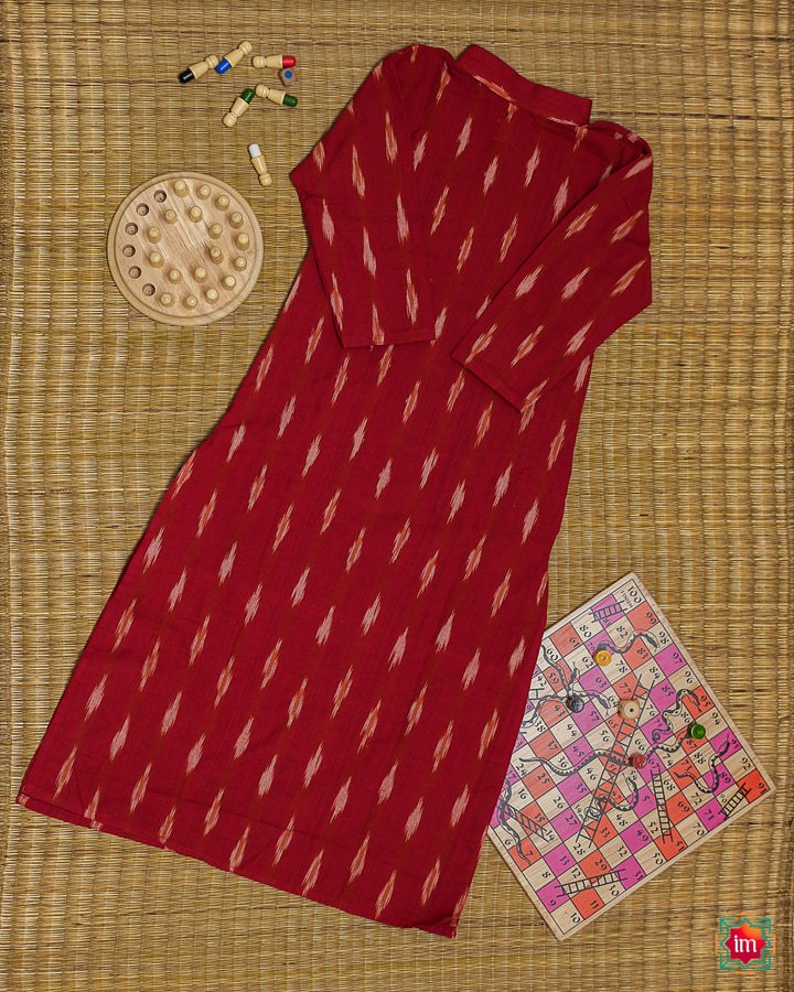 Beautiful red girl back side kurta which is kept on a mat background with some children indoor games which are kept beside.