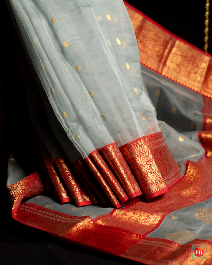 Elegant grey silk saree is pleated and displayed on the floor.