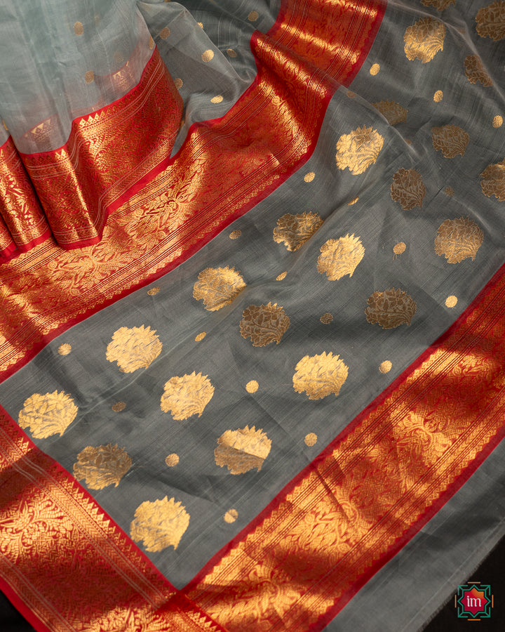 Elegant grey silk saree is pleated and displayed on the floor.