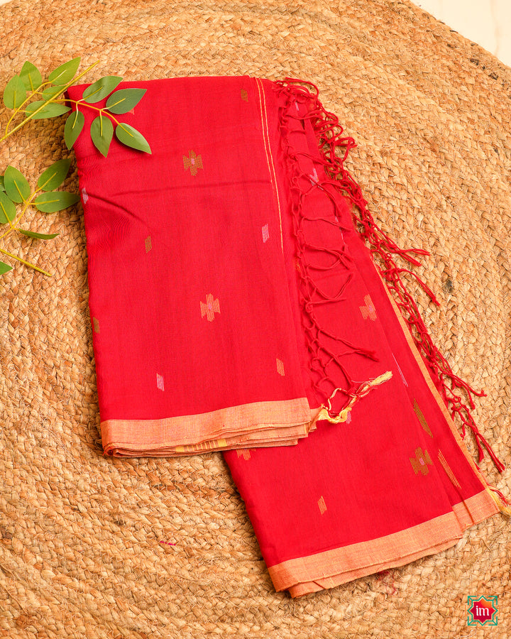 Beautiful red handloom saree is kept on a jute mat.