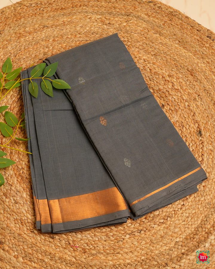 Beautiful grey handloom cotton saree is kept on a jute mat.