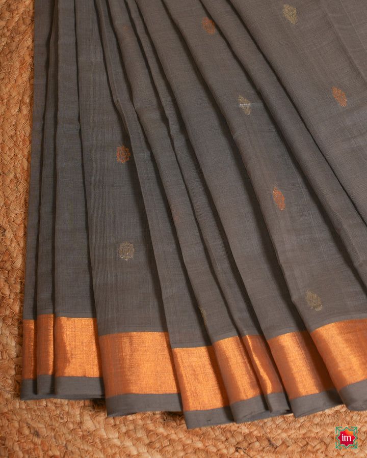 Beautiful grey handloom cotton saree is pleated and displayed on the floor.