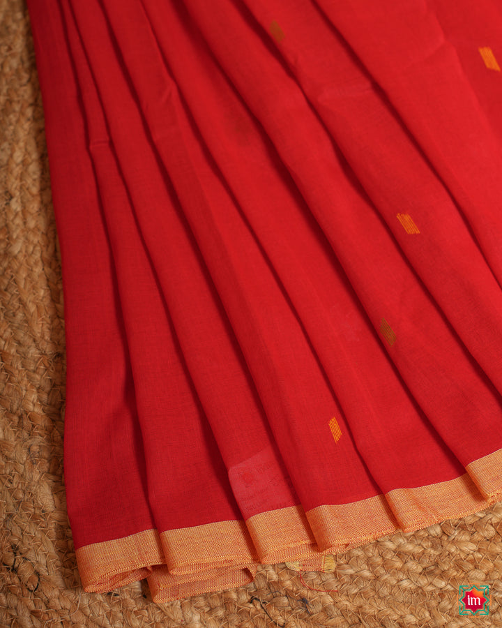 Beautiful red handloom saree is pleated and displayed on the floor.