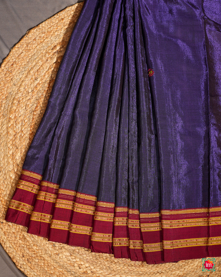Purple saree is pleated and displayed on the floor.