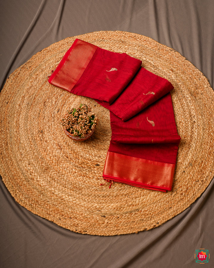 Red handloom cotton saree is kept on a jute mat.