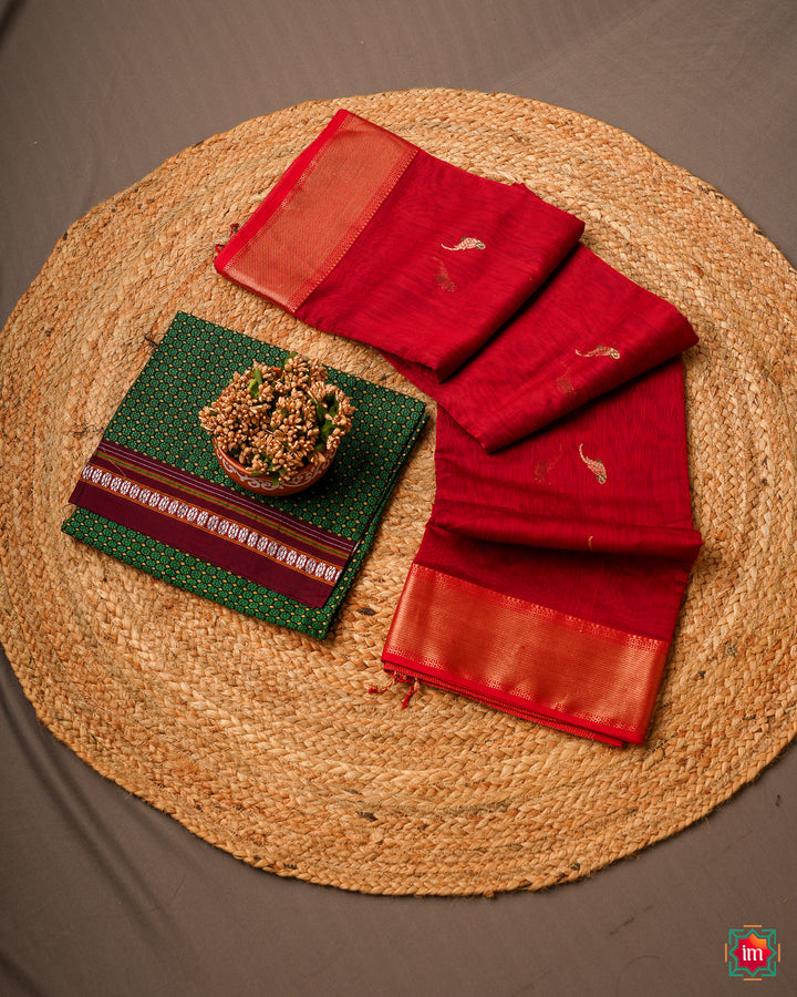 Red handloom cotton saree is kept on a jute mat.