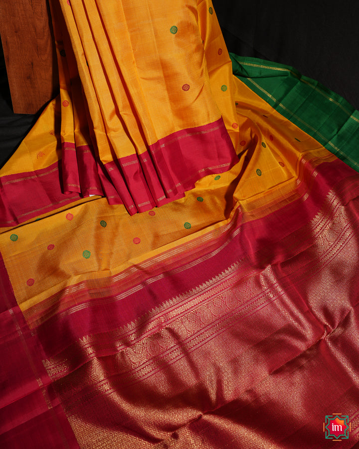 Yellow Red Ganga Jamuna Kanjivaram silk saree is pleated and displayed on the floor.